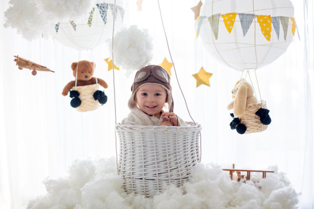 可爱的蹒跚学步的男孩，玩飞机和泰迪熊，气球和身后的玩具图片下载