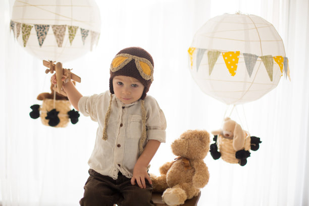 可爱的蹒跚学步的男孩，玩飞机和泰迪熊，气球和身后的玩具图片下载