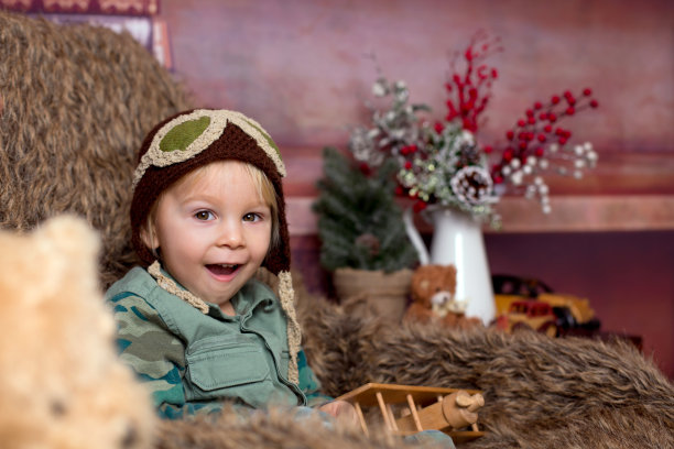 可爱的男孩穿着军装，坐着飞机，坐在沙发椅上，微笑着图片下载