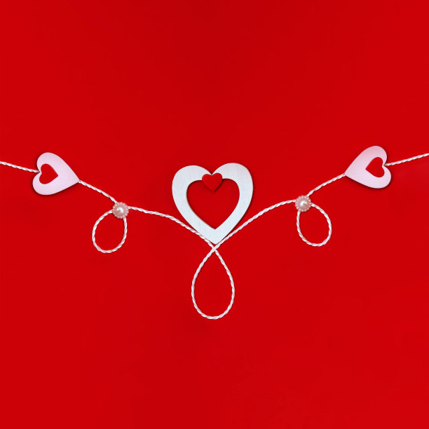 在一个红色的背景与白色和红色的心和一根白色的绳子上的一个情人节作文的俯视图。节日概念，贺卡，背景。图片下载