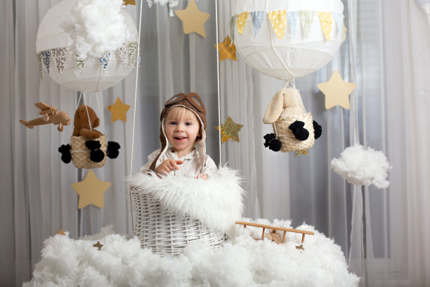 可爱的蹒跚学步的男孩，玩飞机和泰迪熊，气球和身后的玩具图片下载