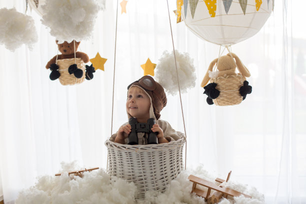 可爱的蹒跚学步的男孩，玩飞机和泰迪熊，气球和身后的玩具图片下载