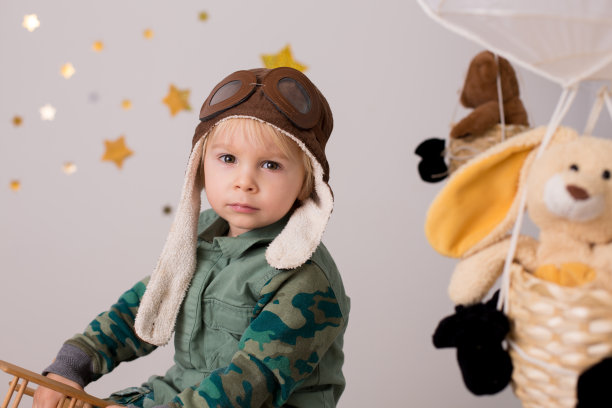 可爱的蹒跚学步的男孩，玩飞机和泰迪熊，气球和身后的玩具图片下载