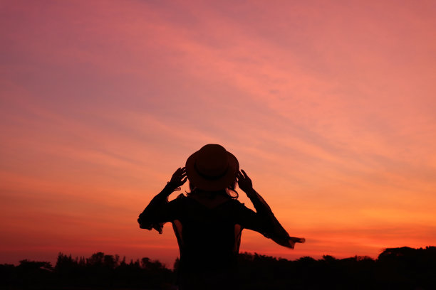 一个女人的剪影映衬着美丽的日出天空图片下载