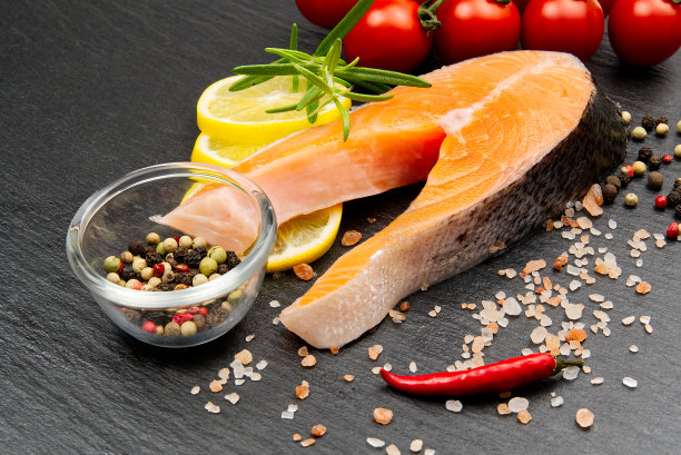 新鲜的生鲑鱼排配胡椒，盐，柠檬和橄榄油在黑色的背景。健康饮食理念。用香料烹饪鱼的准备工作图片下载