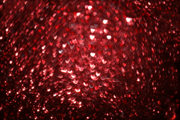 情人节或妇女节的贺卡。红心在抽象模糊的红色背景与散景。节日背景，文字的位置，屏幕上的横幅。图片下载