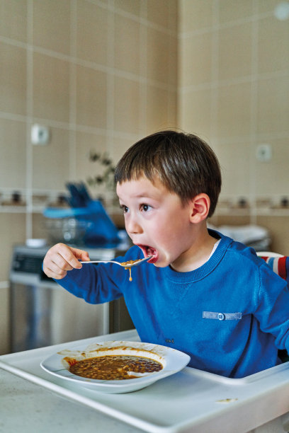 可爱的孩子在婴儿椅上吃蔬菜。图片下载