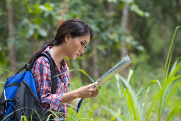 亚洲女性在云杉森林背包旅行的照片，看地图去目的地的路线，这是女性独自旅行的概念图片下载