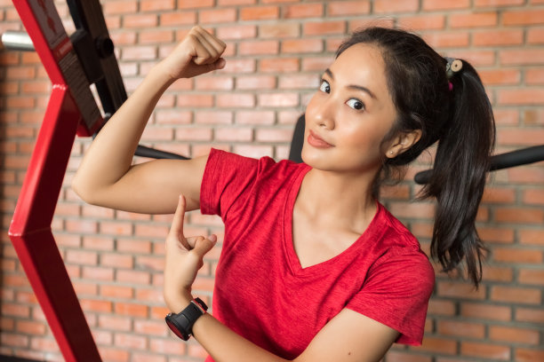 图片的年轻亚洲健康和快乐美丽的健身女运动员在运动服和看摄像机摆姿势在体育馆图片下载