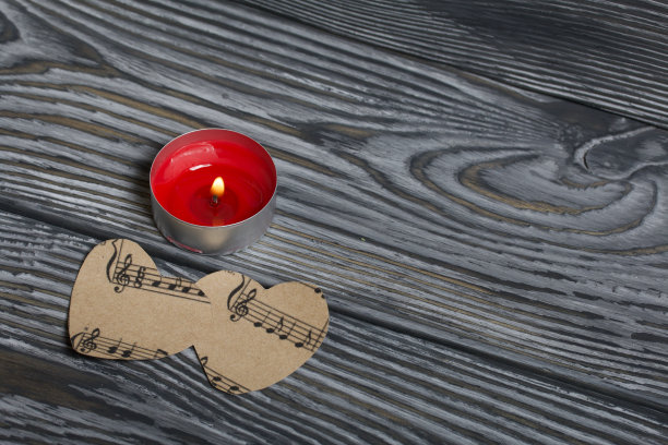 在刷过的木板上燃烧着蜡烛。在纸上剪出两颗带笔记的心图片下载