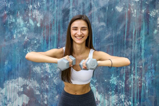做健身运动的女人。年轻女子拿着哑铃在户外摆姿势图片下载