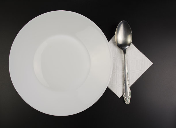 白色的盘子和铁勺放在一张黑色的桌子上图片下载