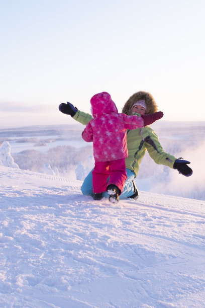 妈妈抱着孩子，孩子高兴地跑向妈妈。一家人穿着冬衣在冬季度假。图片下载