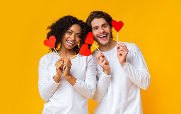 浪漫的多民族夫妇手持红纸红心棒的肖像图片下载
