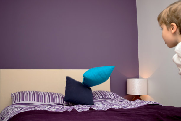 顽皮的男孩把枕头扔在床上。图片下载