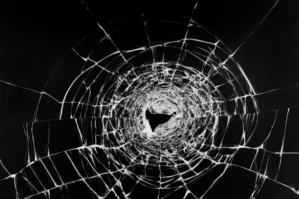 碎玻璃上的裂纹。窗户被枪弹损坏了。一辆汽车的透明挡风玻璃上有一个洞。图片下载