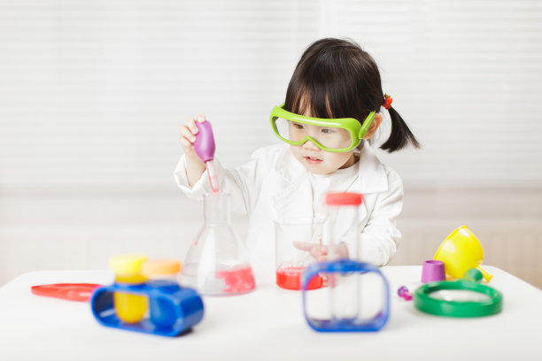 蹒跚学步的女孩在白色背景下扮演科学家的角色图片下载