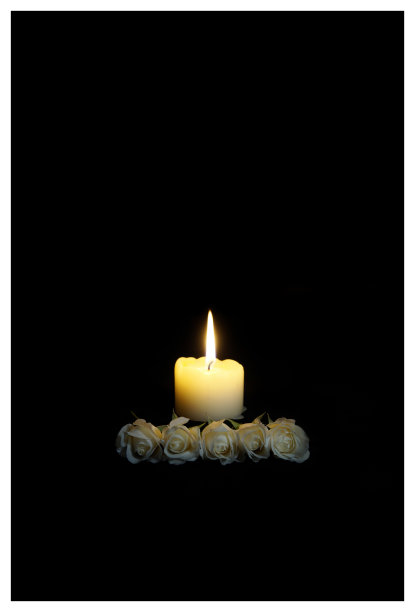 同情卡。在黑暗中点缀着白玫瑰和燃烧的蜡烛。黑色背景中燃烧着的蜡烛。文本的空位置。欣赏，感情恭维，哀痛框架。吊唁卡，祈祷和最深切的同情概念葬礼的象征。图片下载