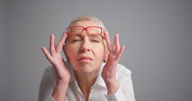 视力不佳的老妇人戴着灰色背景的眼镜图片下载