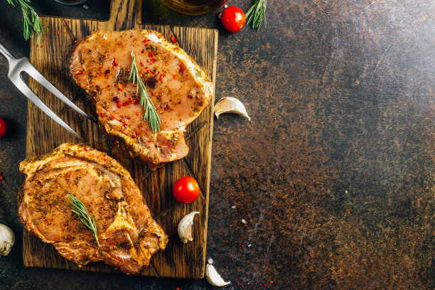 在切菜板上腌制的生猪肉排。准备做饭。黑暗的照片。前视图。图片下载
