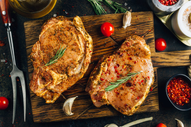 在切菜板上腌制的生猪肉排。准备做饭。黑暗的照片。前视图。图片下载