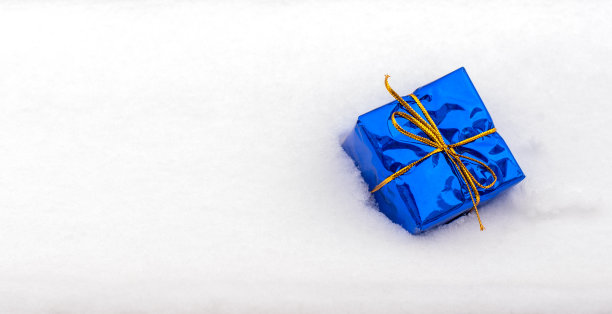 用金色丝带包裹的经典蓝色礼盒躺在洁白的雪地里。庆祝活动的背景。冬天的生日，派对，乐趣，欢乐的概念。问候、邀请卡。平铺，俯视图，拷贝空间。图片下载