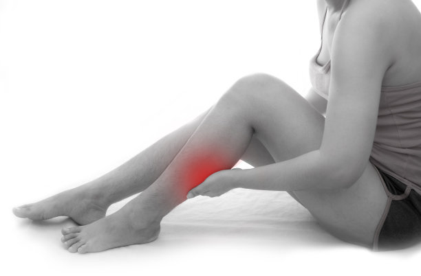 女人小腿感到疼痛在白色的背景上，女人遭受腿部疼痛图片下载