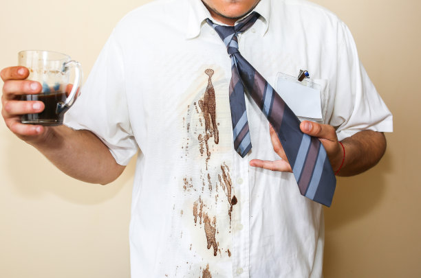 一个办公室职员把咖啡洒到白衬衫上。职业倦怠。不高兴的经理手里拿着马克杯。工作的压力。绝望的人。图片下载