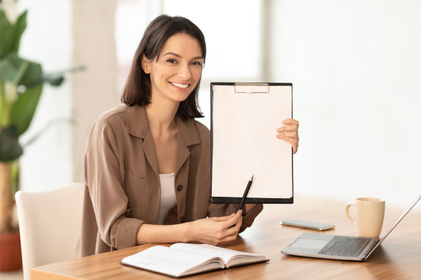 微笑的女人在办公室展示空白的剪贴板图片下载