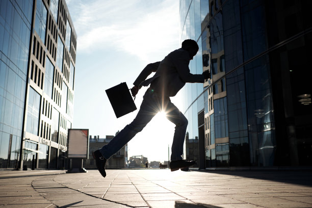 非裔美国白领在阳光下奔向现代办公大楼的身影图片下载