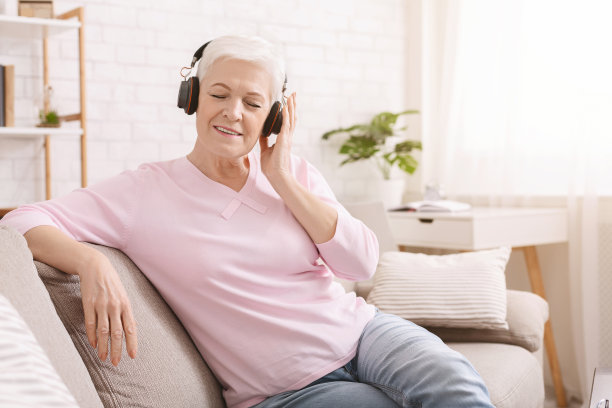 老年妇女用耳机听有声书，有自由空间素材图片