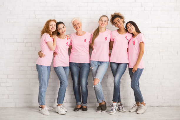 多种族女性穿着乳腺癌t恤，站在室内拥抱图片下载