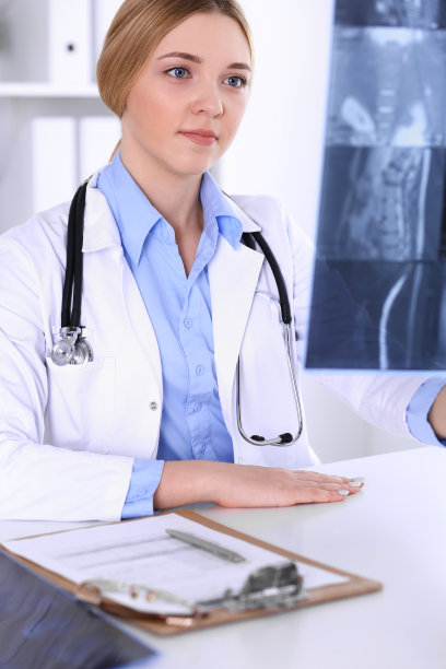 一位女医生在医院窗户附近检查x光照片。在工作中的外科医生或整形外科医生医疗保健理念。蓝色的治疗师衬衫看起来不错图片下载