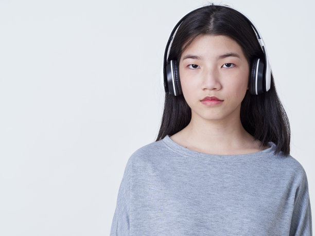 小女孩戴着耳机听白色背景音乐的肖像图片下载