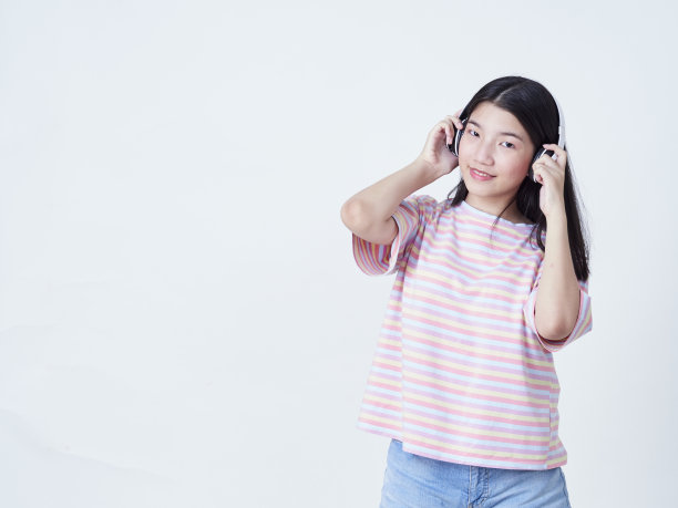 小女孩戴着耳机听白色背景音乐的肖像图片下载