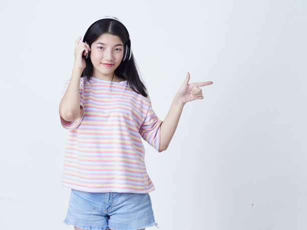 小女孩戴着耳机听白色背景音乐的肖像图片下载