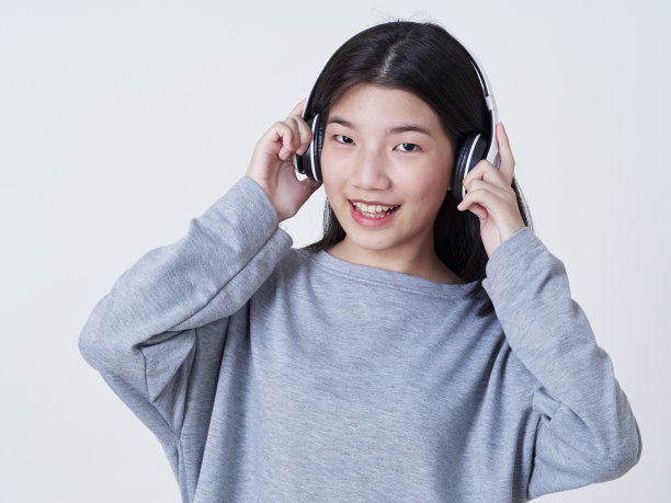 小女孩戴着耳机听白色背景音乐的肖像图片下载