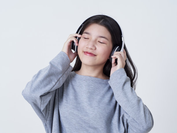 小女孩戴着耳机听白色背景音乐的肖像图片下载