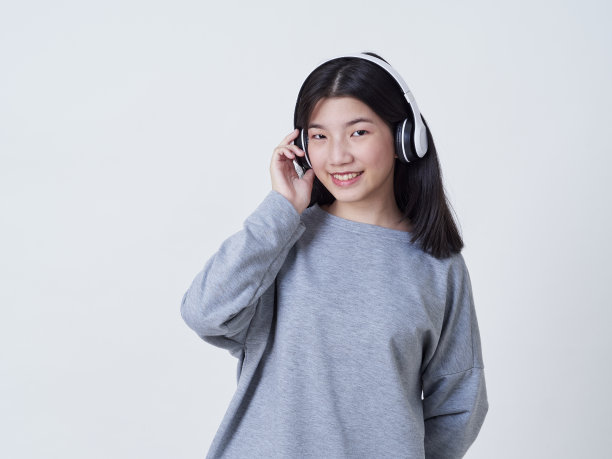 小女孩戴着耳机听白色背景音乐的肖像图片下载