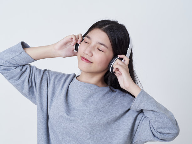 小女孩戴着耳机听白色背景音乐的肖像图片下载
