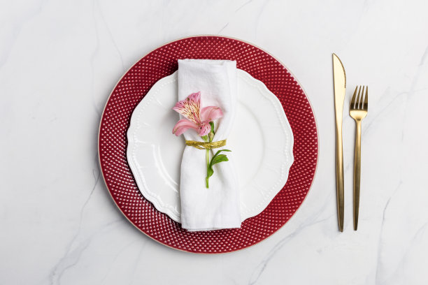 假日餐桌上摆放着金色的刀叉和餐巾上的鲜花图片下载