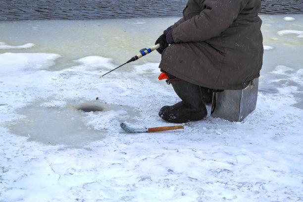 一位老妇人从河的冰下抓鱼。冬季钓鱼。图片下载