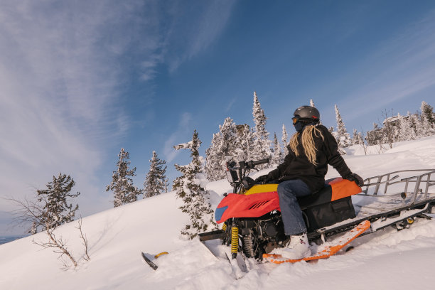 在冬天的森林里驾驶雪地摩托的漂亮女人。图片下载