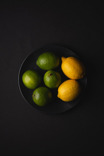 酸橙和柠檬酸水果在黑色的盘子，在忧郁的黑色背景，俯视图，维生素和健康的食物图片下载