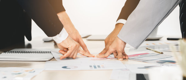 商务人士的手和手指指着会议桌上的一点，以共同瞄准同一个商业目标的概念图片下载