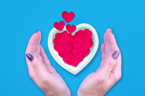女性的手和纸心飞出陶瓷心。情人节的背景。图片下载