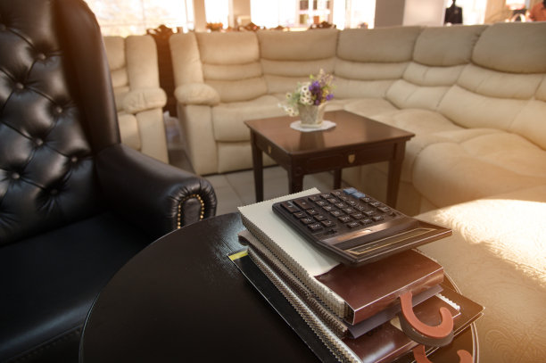 他的工作地点是一家家具店的老板，店里有一把昂贵的皮革扶手椅、一张沙发桌、几份家具目录和一台计算器。舒适工作环境的概念图片下载