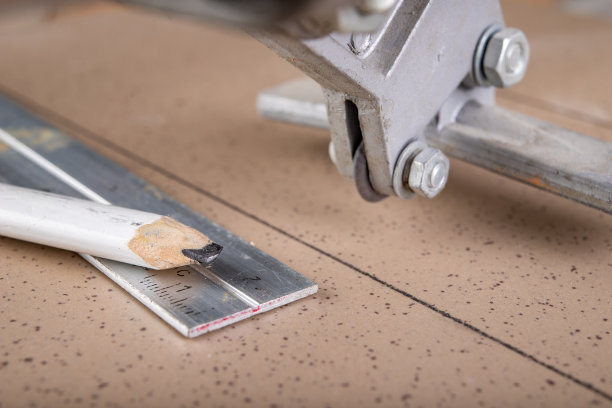 在家庭作坊切割瓷砖。在工作台上铺瓷砖。黑暗的背景。图片下载