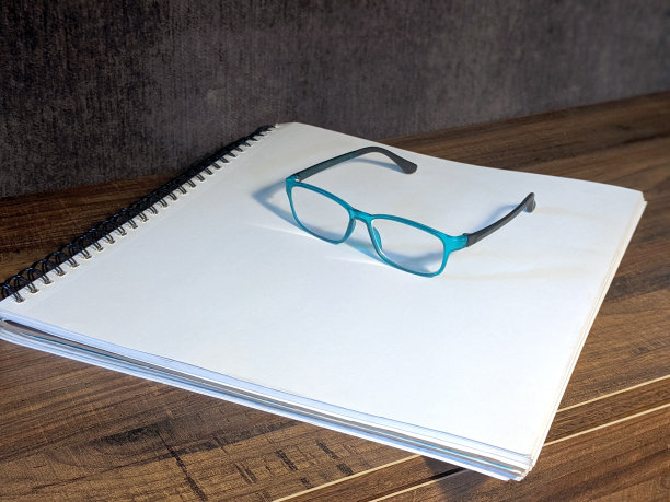 在一个白色的螺旋式绘图笔记本上放着眼镜图片下载
