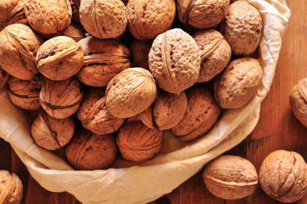 整个核桃放在质朴的旧木桌上，核桃放在可重复使用的布袋里图片下载